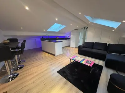 a living room with a black couch and a kitchen at Le Loft Cannes in Cannes