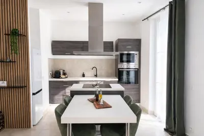 a kitchen with a white table and a sink at Apparemment cosy avec balcon plein centre de Cannes - Carla home in Cannes