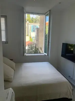 a bed in a room with a window at Apparemment cosy avec balcon plein centre de Cannes - Carla home in Cannes