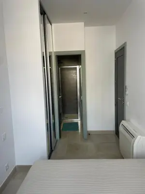 a white room with a bed and a hallway at Apparemment cosy avec balcon plein centre de Cannes - Carla home in Cannes