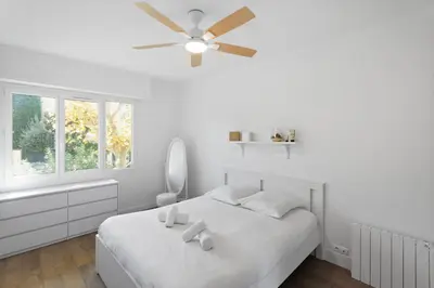 a white bedroom with a bed with a ceiling fan at Le Tivoli - City Centre - Quiet - Spacious in Le Cannet