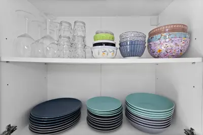 a shelf filled with plates and glass jars at Le Tivoli - City Centre - Quiet - Spacious in Le Cannet