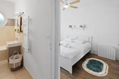 a white bedroom with a bed and a bathroom at Le Tivoli - City Centre - Quiet - Spacious in Le Cannet
