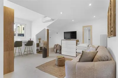 a white living room with a couch and a tv at Studio V - à 2 min du Palais - Hypercentre - Calme in Cannes