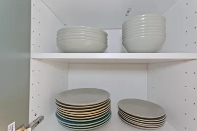 a group of plates on shelves in a kitchen at Le Farniente - Peaceful - Parking - AC - Balcony in Le Cannet