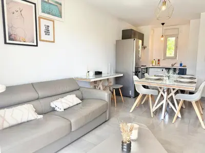 a living room with a couch and a kitchen at T2 - piscine - garage privé - 5 min de Cannes in Le Cannet