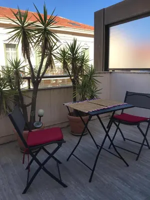 a table and chairs on a balcony with palm trees at Gray d' Albion Apartment in Cannes