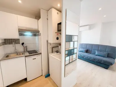 a kitchen and a living room with a blue couch at 285G Studio 5mn Palais in Cannes