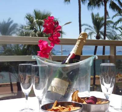 a bottle of champagne in a bucket on a table with glasses at Appartement Rottaro luxueux 2 ch 2 sdb face à la mer in Cannes