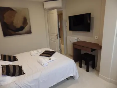 a bedroom with two beds and a desk and a television at Appartement Rottaro luxueux 2 ch 2 sdb face à la mer in Cannes