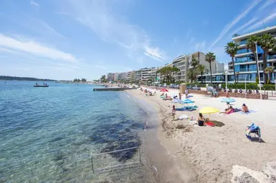 a beach with people sitting on the sand and the water at Apartment Seaside in Cannes