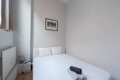 a bedroom with a white bed with a black towel on it at Ideal Groupes & Familles 3 chambres - 10 pers - Hyper-centre Cannes in Cannes