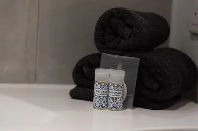 a bottle of soap next to a pile of towels at Ideal Groupes & Familles 3 chambres - 10 pers - Hyper-centre Cannes in Cannes