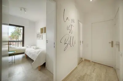 a white room with a bed and a bedroom with a door at Calme et Lumineux 2 chambres BALCON Vue MER-FORVILLE A2B262 in Cannes