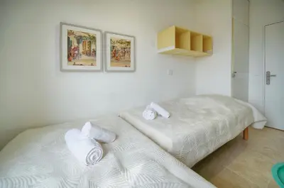 a white bedroom with two beds and two pictures on the wall at Calme et Lumineux 2 chambres BALCON Vue MER-FORVILLE A2B262 in Cannes