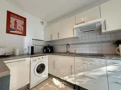 a kitchen with white cabinets and a washer and dryer at DAPHNE, appartement piscine in Cannes