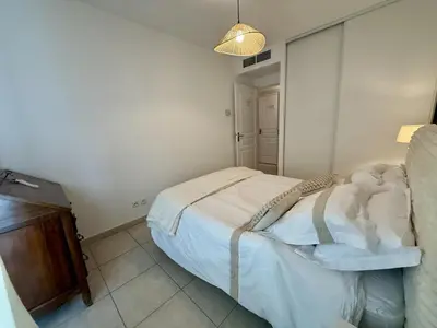 a small bedroom with a bed and a lamp at DAPHNE, appartement piscine in Cannes