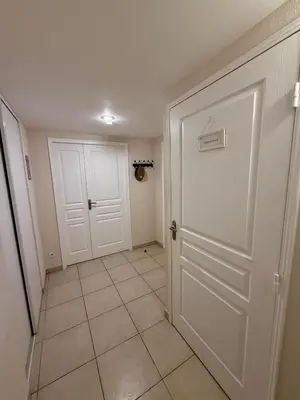 a hallway with a white door and a tiled floor at DAPHNE, appartement piscine in Cannes