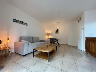 a living room with a couch and a table at DAPHNE, appartement piscine in Cannes