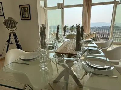 a dining room with a glass table and white chairs at Grande villa, 6 chambres, vue mer, montagne & ville de Cannes in Le Cannet