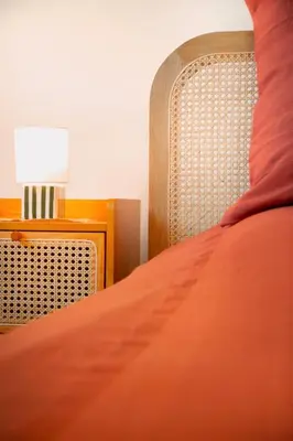 a bed with an orange comforter and a table with a lamp at Apartment near Croisette and Cannes festival in Le Cannet