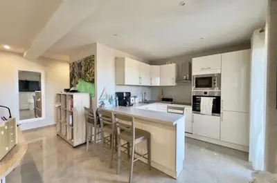 a kitchen with white cabinets and a bar with stools at Eryvazur in Vallauris