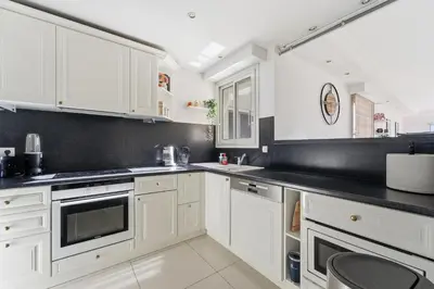 a kitchen with white cabinets and black counter tops at Appartement Margot - Welkeys in Le Cannet