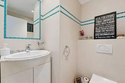 a white bathroom with a sink and a mirror at Appartement Margot - Welkeys in Le Cannet