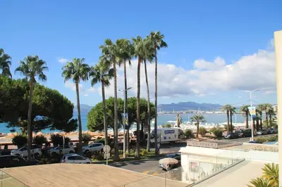 a view of a parking lot with palm trees and the ocean at Superbe 2 pièces - Première ligne Croisette in Cannes