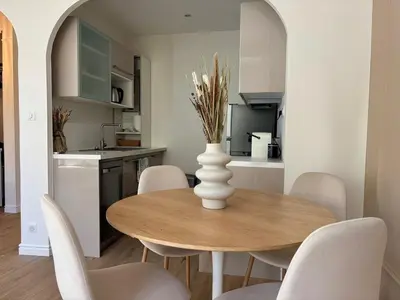 a dining room table with white chairs and a vase with flowers at Appartement cosy - 4 personnes - Centre Cannes in Cannes