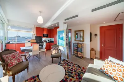 a living room with red cabinets and a table and chairs at COZYSTAY - Charmant 3 pièces en dernier étage in Cannes