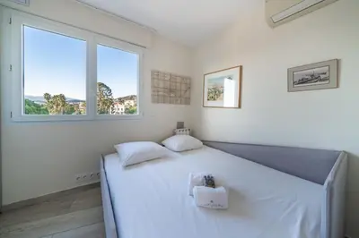 a bedroom with a large white bed with two windows at COZYSTAY - Charmant 3 pièces en dernier étage in Cannes