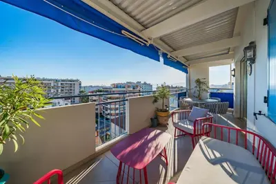 a balcony with red chairs and a view of a city at COZYSTAY - Charmant 3 pièces en dernier étage in Cannes