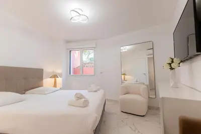 a white bedroom with two beds and a chair at Rez-de-Jardin à Cannes Centre - Luxe & Design in Cannes