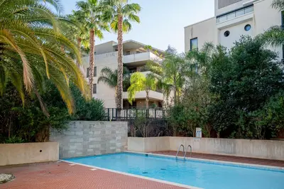 a swimming pool in front of a building with palm trees at Rez-de-Jardin à Cannes Centre - Luxe & Design in Cannes