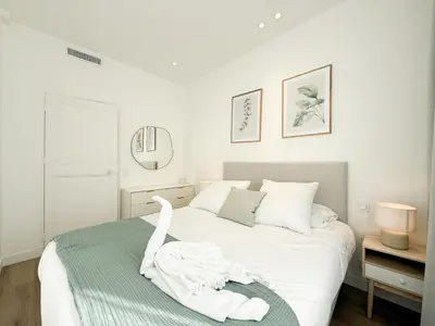 a white bedroom with a bed with a towel on it at The Cosy Clémenceau in Cannes