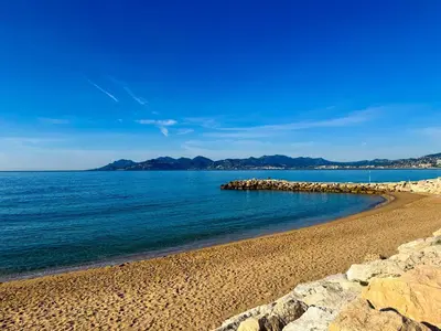a beach with rocks and the ocean on a clear day at The Cosy Clémenceau in Cannes
