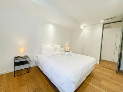 a white bedroom with a large bed and two lamps at Atelier Meynadier in Cannes