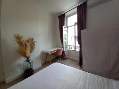 a bedroom with a bed and a window with a table at Lecerf in Cannes