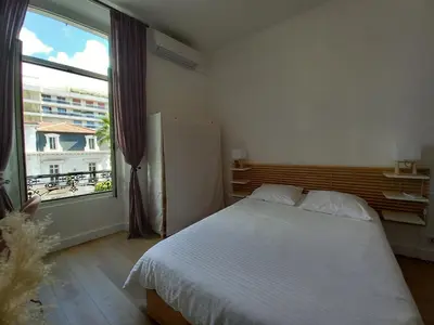 a bedroom with a bed and a large window at Lecerf in Cannes