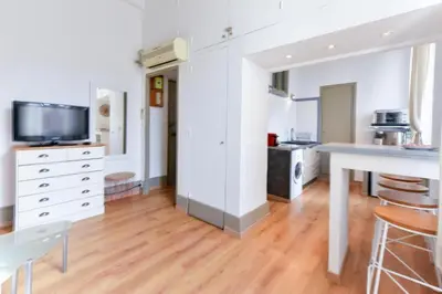 a kitchen with white walls and wooden floors and a table at Studio élégant pour 4 personnes, à quelques pas de la Croisette in Cannes