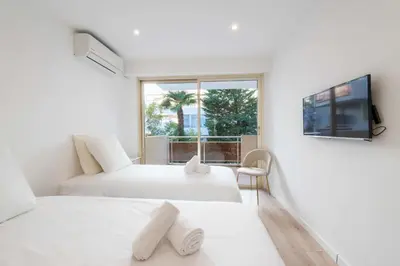 two beds in a white room with a window at 3-Br Crossing Apartment Palm Beach in Cannes