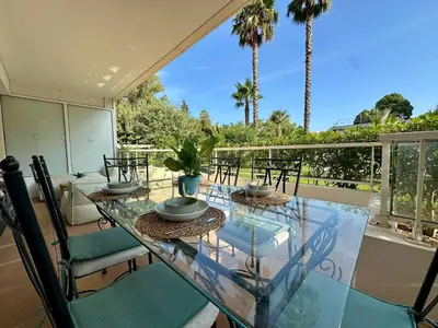 a glass table and chairs on a balcony with palm trees at Le Casta - Terrasse spacieuse - à 2 min des plages in Cannes