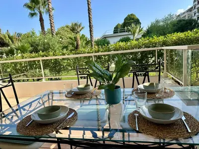 a glass table with plates and bowls on a balcony at Le Casta - Terrasse spacieuse - à 2 min des plages in Cannes