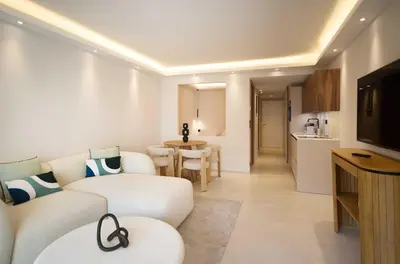 a living room with a white couch and a kitchen at A C apt in the heart of Cannes—Croisette Beaches in Cannes