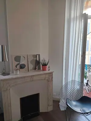 a living room with a fireplace with a chair and a table at Cannes centre superbe 3 pièces moderne 10 min à pied du Palais des festivals et croisette in Cannes