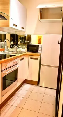a kitchen with white cabinets and a sink and a refrigerator at Beautiful 36m2 studio apartment & 50m2 terrace in Cannes