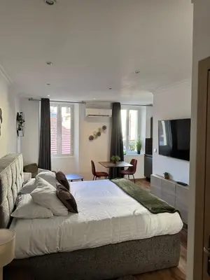 a bedroom with a large bed and a living room at King size studio Rue Félix Faure 100 m Palais et plage in Cannes