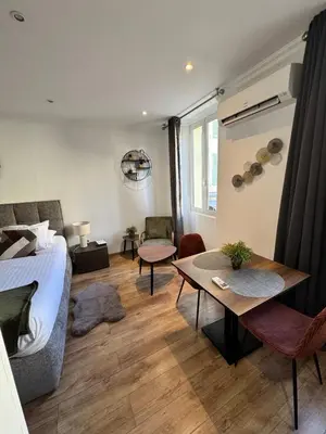 a bedroom with a bed and a table and a couch at King size studio Rue Félix Faure 100 m Palais et plage in Cannes
