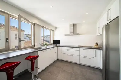 a kitchen with white cabinets and red stools at -CLR- Stunning suite with terrace in Cannes